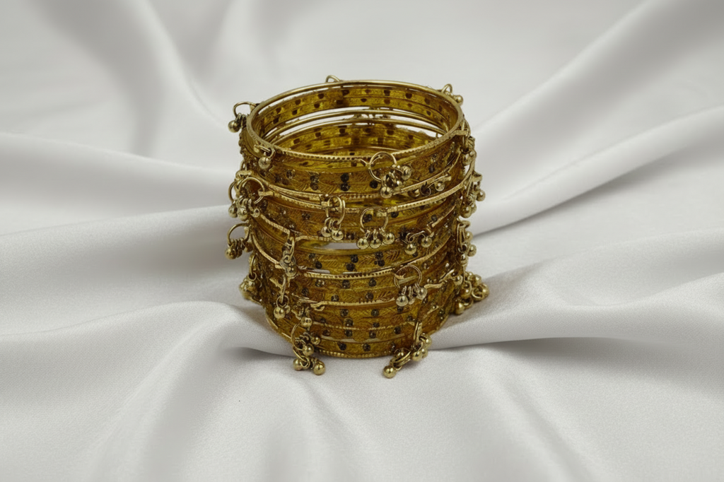 Stack of gold bangles on a white fabric background