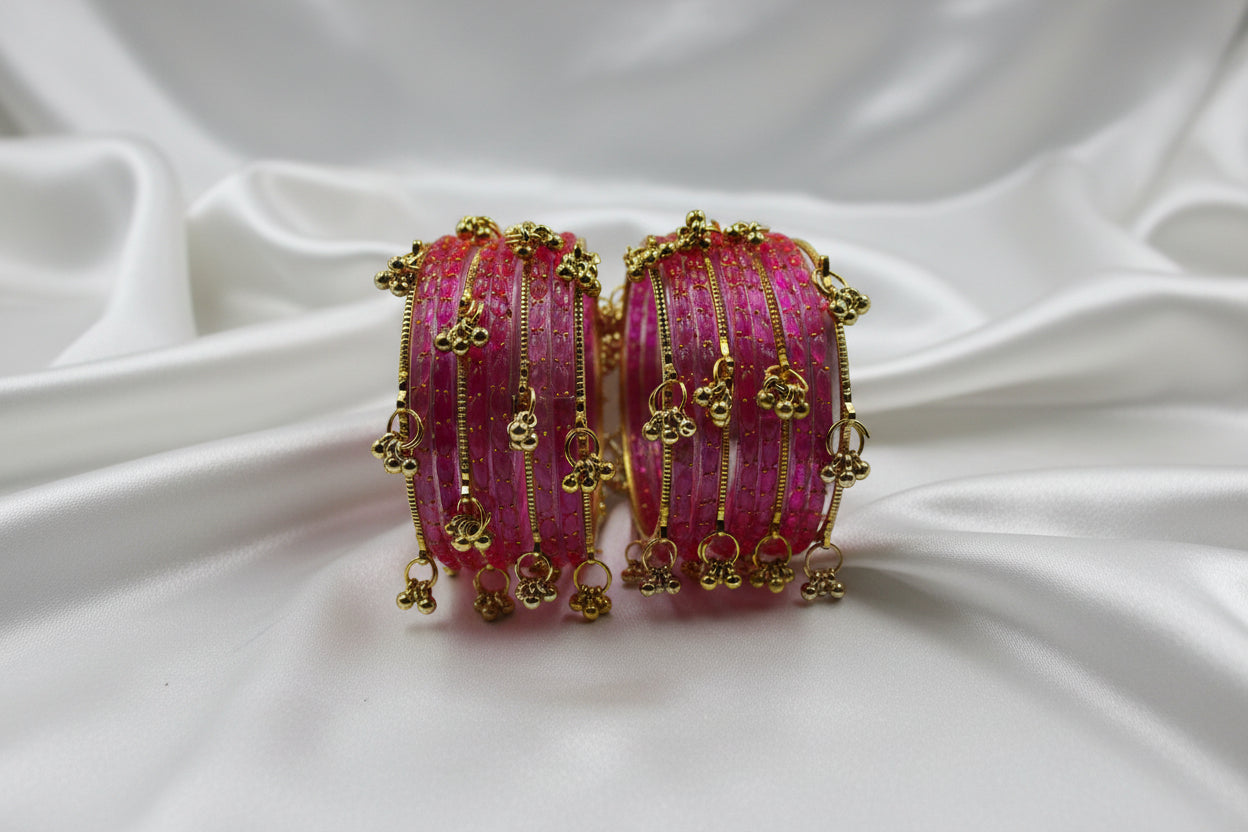 Pink beaded bracelets with gold accents on a white surface